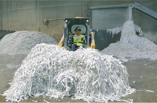 man in a forklift surrounded by piles of shredded paper
