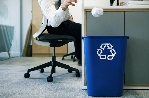 person throwing a paper ball into a recycling bin