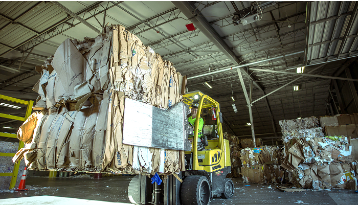 Wide angle shot of a forklift transporting a stack of bales in a warehouse