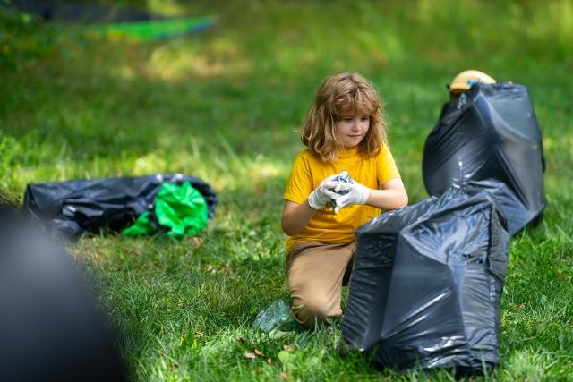 A child picks up litter in a park-like setting