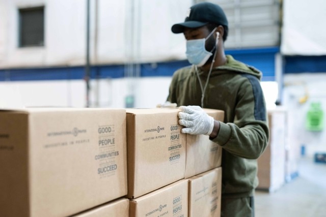 A volunteer stacks International Paper community boxes at a food bank