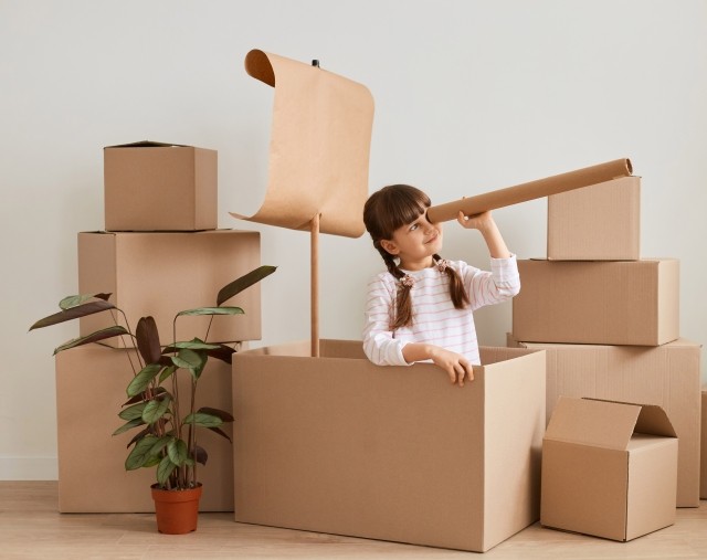 A little girl plays make-believe with corrugated boxes