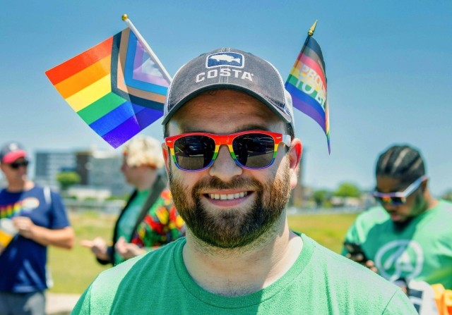 A man smiles with rainbow flags