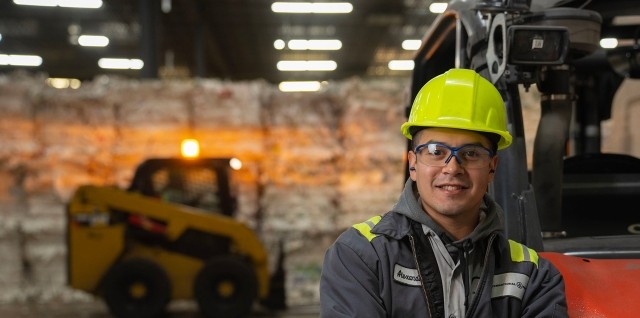 worker leaning on a forklift, arms crossed